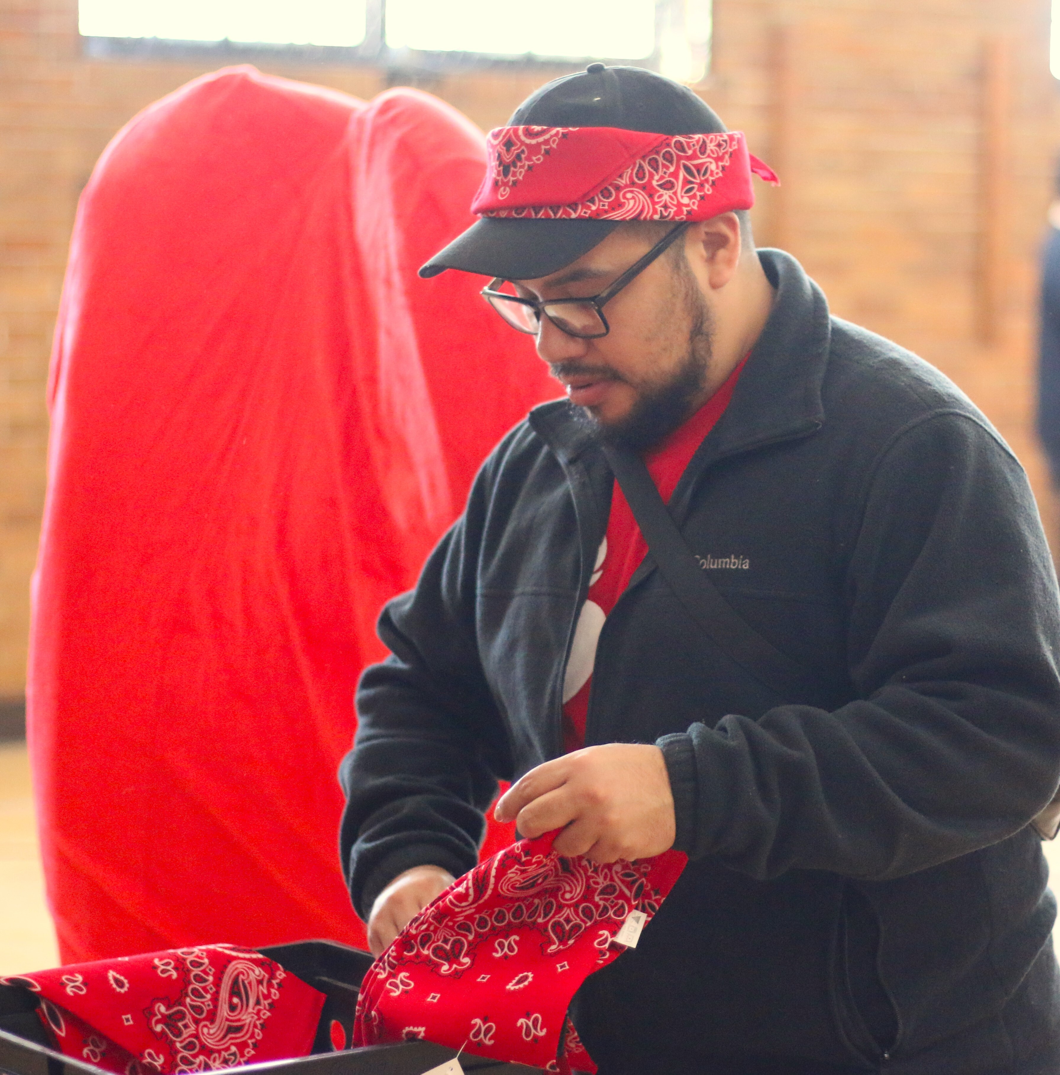 Javier Cervantes hands out red bandanas to North Park Montessori students as they enter the gym for their Wear Red Day Dance Party